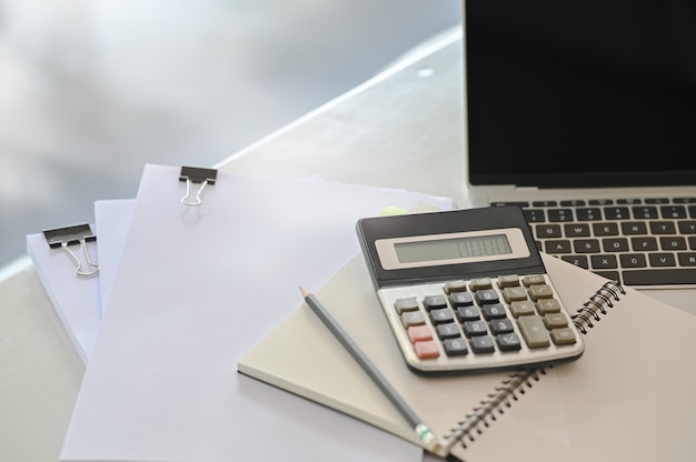 Concepto de finanzas, calculadora, computadora portátil y papeleo en la mesa de oficina.