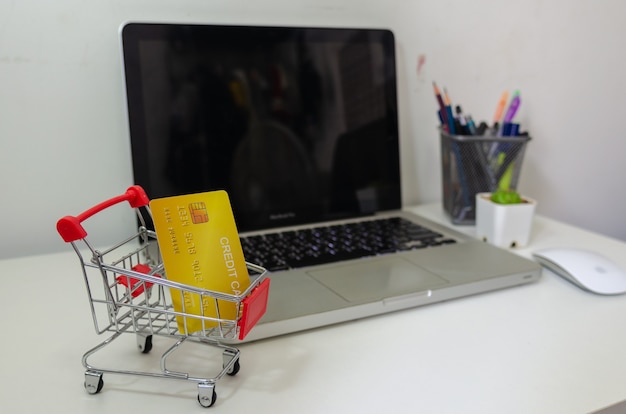 Concepto de finanzas empresariales. la tarjeta de crédito está en el carrito en el escritorio de la computadora. Negocio de marketing y compras online