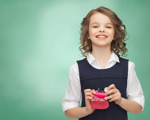 concepto de finanzas, infancia, personas, dinero y ahorro - niña feliz con monedero y moneda de euro sobre fondo de pizarra verde