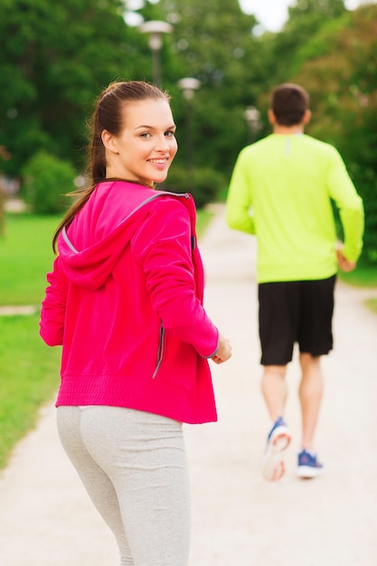 concepto de fitness, deporte, amistad y estilo de vida - pareja sonriente corriendo al aire libre