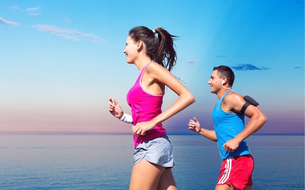 Concepto de fitness, deporte, amistad y estilo de vida - pareja sonriente corriendo juntos