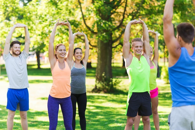 concepto de fitness, deporte, amistad y estilo de vida saludable - grupo de amigos adolescentes felices o deportistas haciendo ejercicio y estirando las manos en el campo de entrenamiento