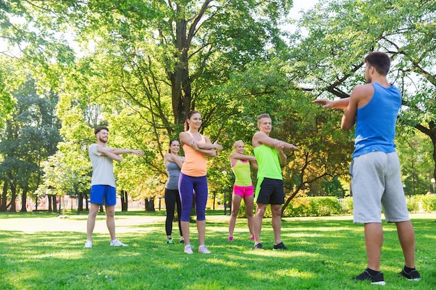 concepto de fitness, deporte, amistad y estilo de vida saludable - grupo de amigos adolescentes felices o deportistas haciendo ejercicio y estirando las manos en el campo de entrenamiento