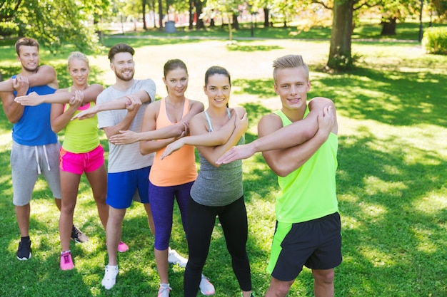 concepto de fitness, deporte, amistad y estilo de vida saludable - grupo de amigos adolescentes felices o deportistas haciendo ejercicio y estirando las manos en el campo de entrenamiento