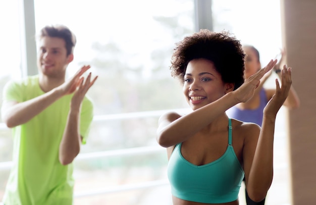 concepto de fitness, deporte, danza y estilo de vida - grupo de gente sonriente con entrenador bailando zumba en el gimnasio o en el estudio