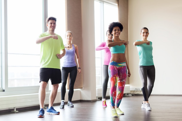 concepto de fitness, deporte, danza y estilo de vida saludable - grupo de gente sonriente con entrenador bailando en el gimnasio o en el estudio