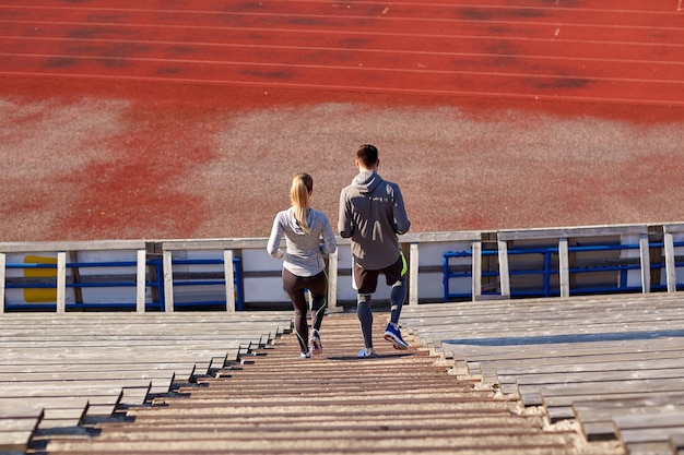 concepto de fitness, deporte, ejercicio y estilo de vida - pareja caminando abajo en el estadio