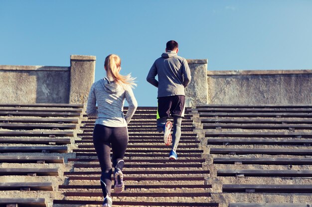 concepto de fitness, deporte, ejercicio y estilo de vida - pareja corriendo arriba en el estadio