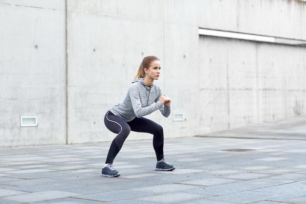 concepto de fitness, deporte, ejercicio y estilo de vida saludable - mujer haciendo sentadillas al aire libre