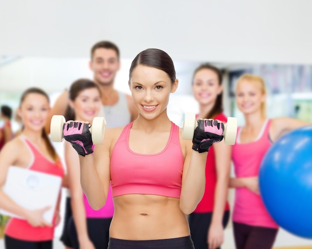 concepto de fitness, deporte, entrenamiento y estilo de vida - entrenador personal con un grupo de personas sonrientes en el gimnasio