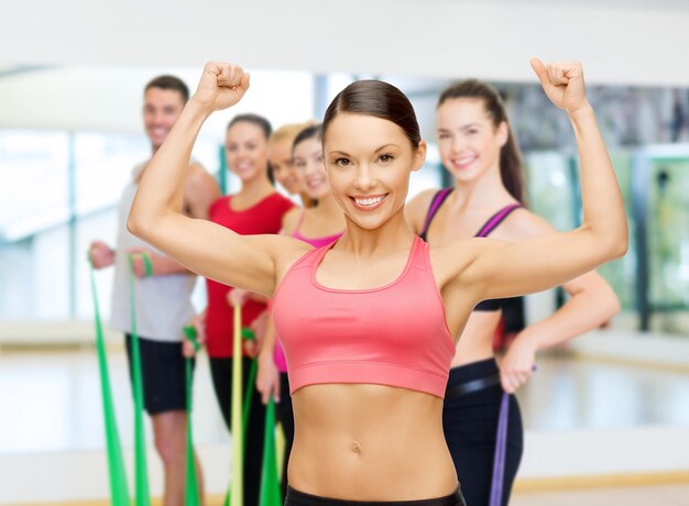 concepto de fitness, deporte, entrenamiento y estilo de vida - entrenador personal con un grupo de personas sonrientes en el gimnasio