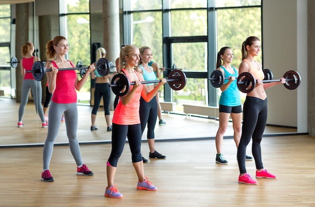 concepto de fitness, deporte, entrenamiento y estilo de vida - grupo de mujeres con pesas en el gimnasio