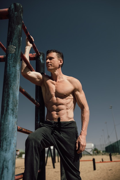 Concepto de fitness, deporte, entrenamiento y estilo de vida - joven haciendo ejercicio en barra horizontal en la playa. Foto de alta calidad