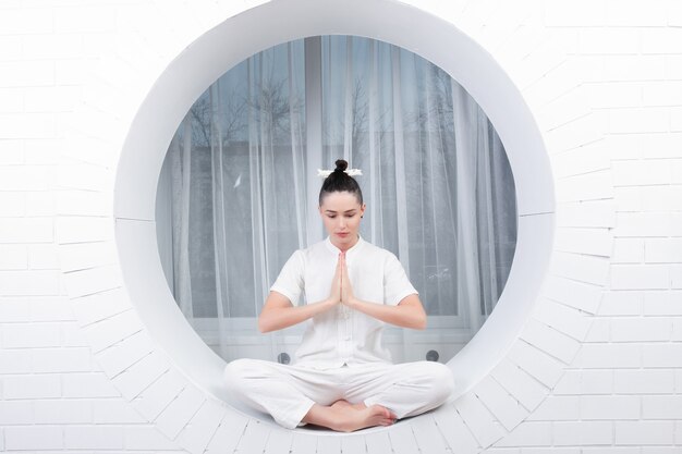 Concepto de fitness, deporte, entrenamiento y estilo de vida - mujer joven haciendo ejercicio de yoga. Retrato de joven hermosa en ropa deportiva blanca haciendo práctica de yoga.Mujer haciendo ejercicio de estiramiento