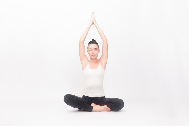 Concepto de fitness, deporte, entrenamiento y estilo de vida - mujer joven haciendo ejercicio de yoga. Retrato de joven hermosa en ropa deportiva blanca haciendo práctica de yoga.Mujer haciendo ejercicio de estiramiento