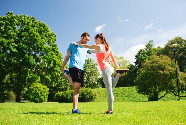 Foto concepto de fitness, deporte, entrenamiento y estilo de vida - pareja sonriente estirando al aire libre