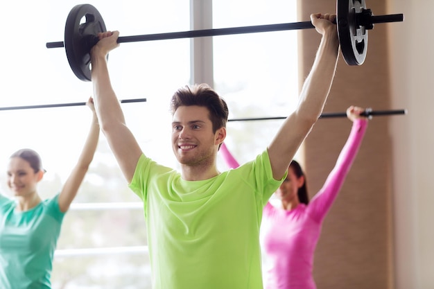 concepto de fitness, deporte, entrenamiento, gimnasio y estilo de vida - grupo de personas haciendo ejercicio con pesas en el gimnasio