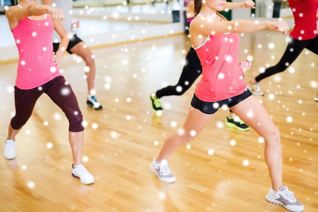 concepto de fitness, deporte, entrenamiento, gimnasio y estilo de vida - grupo de personas sonrientes con entrenador haciendo ejercicio en el gimnasio