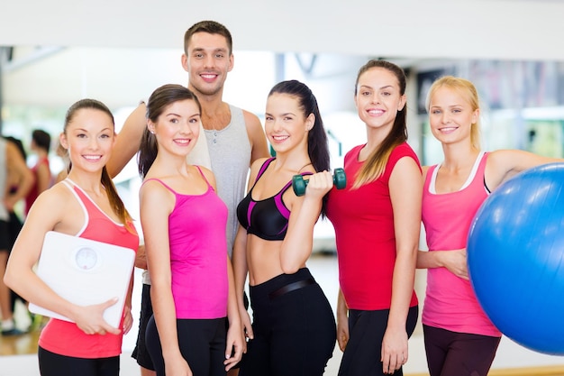 concepto de fitness, deporte, entrenamiento, gimnasio y estilo de vida - grupo de personas sonrientes en el gimnasio