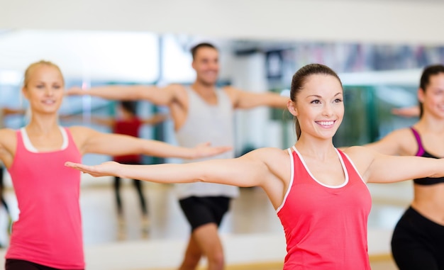 concepto de fitness, deporte, entrenamiento, gimnasio y estilo de vida - grupo de personas sonrientes haciendo ejercicio en el gimnasio