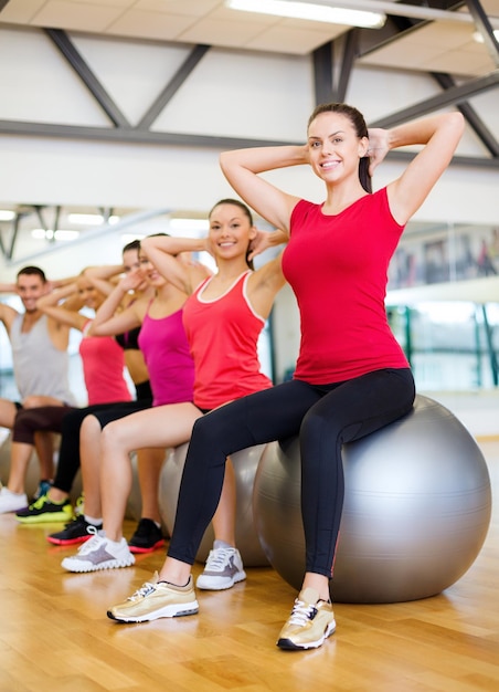 concepto de fitness, deporte, entrenamiento, gimnasio y estilo de vida: grupo de personas sonrientes que se ejercitan en la clase de pilates