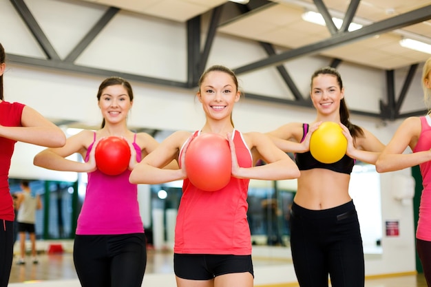 Foto concepto de fitness, deporte, entrenamiento, gimnasio y estilo de vida - grupo de personas sonrientes trabajando con pelotas de estabilidad en el gimnasio