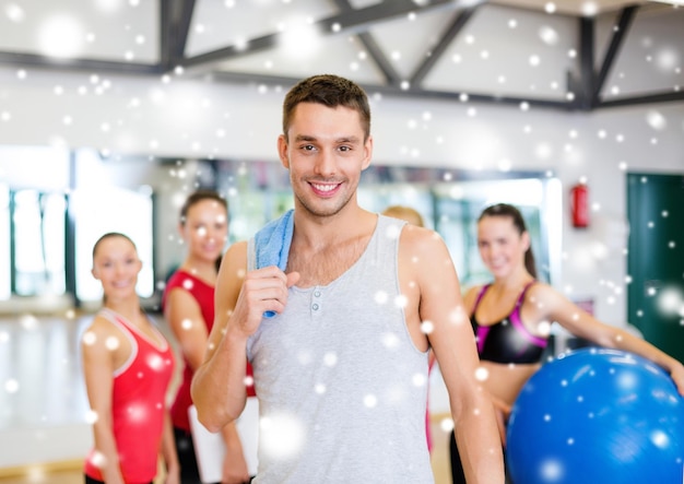 concepto de fitness, deporte, entrenamiento, gimnasio y estilo de vida - hombre sonriente de pie delante del grupo de personas en el gimnasio