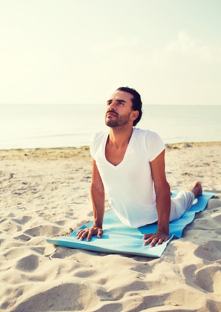 Foto concepto de fitness, deporte y estilo de vida - hombre haciendo ejercicios de yoga acostado en la alfombra al aire libre