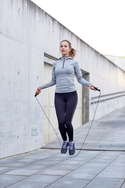 concepto de fitness, deporte, gente, ejercicio y estilo de vida - mujer saltando con cuerda de salto al aire libre