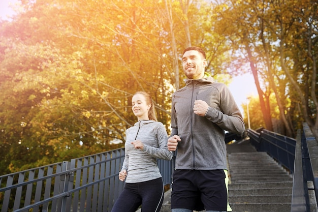 concepto de fitness, deporte, gente y estilo de vida - pareja feliz corriendo escaleras abajo en la ciudad