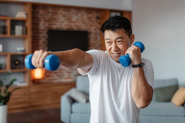 Concepto de fitness y deporte Hombre maduro activo haciendo ejercicio con dos pesas y boxeando disfrutando del entrenamiento doméstico