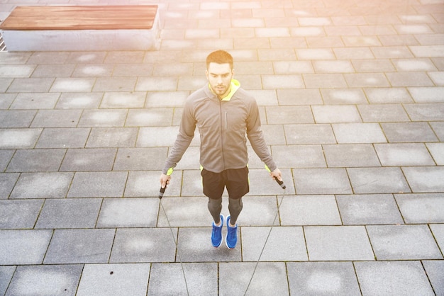 Concepto de fitness, deporte, personas, ejercicio y estilo de vida - hombre saltando con saltar la cuerda al aire libre