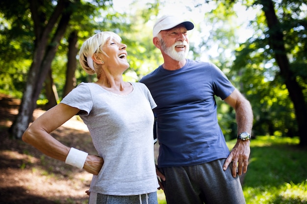 Concepto de fitness, deporte, personas, ejercicio y estilo de vida - pareja senior corriendo