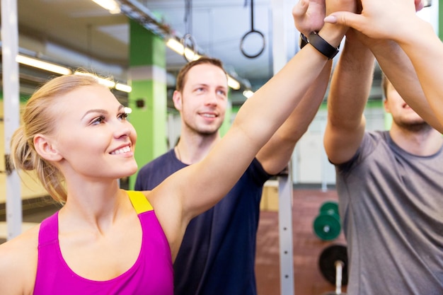 concepto de fitness, deporte y trabajo en equipo: grupo de gente feliz o amigos chocando los cinco en el gimnasio