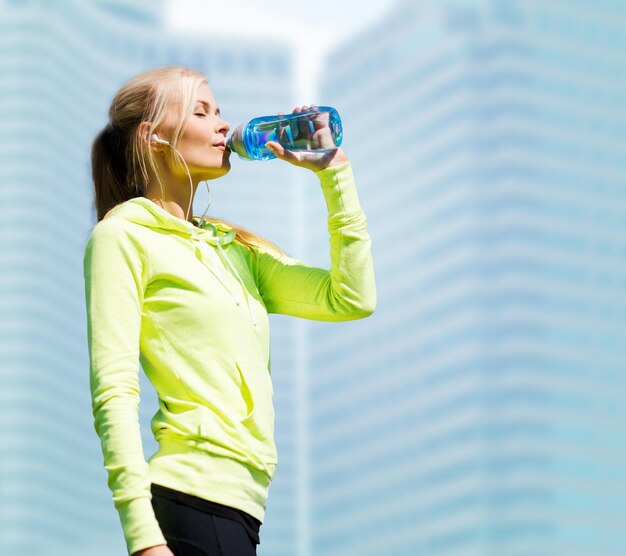 concepto de fitness y estilo de vida - mujer bebiendo agua después de hacer deporte al aire libre