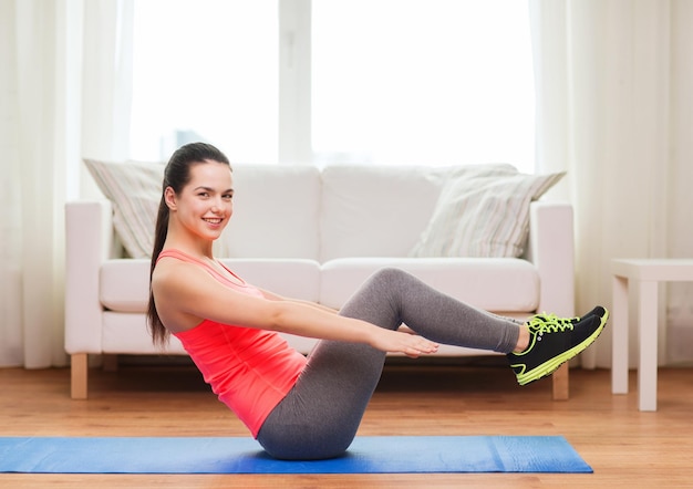 concepto de fitness, hogar y dieta - adolescente sonriente haciendo ejercicio en el suelo en casa