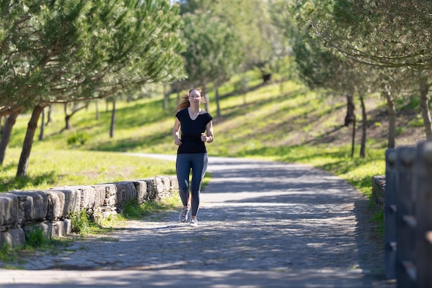 Concepto de fitness una mujer adulta con gafas trotando en el parque verde