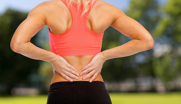 concepto de fitness, salud y medicina - cerca de mujer deportiva tocando su espalda