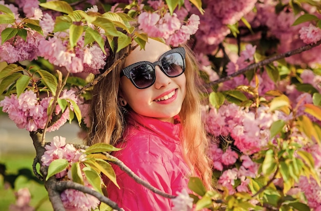 Concepto de flor de sakura Hermosa flor y belleza femenina Fondo de flor de cerezo de niña Árbol de sakura floreciendo Parque y jardín Niña pequeña en flor de primavera Disfruta del olor a flor tierna