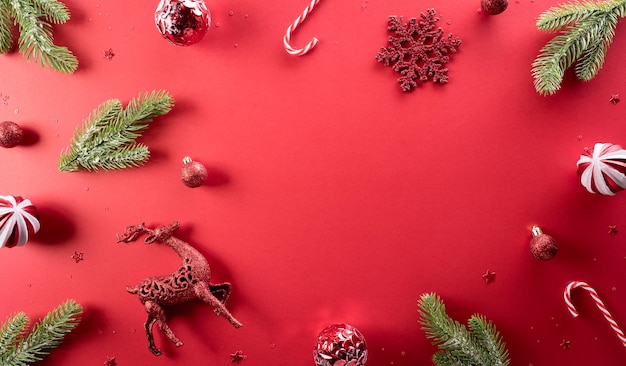 Concepto de fondo de Navidad y año nuevo Vista superior de la decoración navideña hecha de bolas de Navidad de copos de nieve y ramas de pino sobre fondo rojo