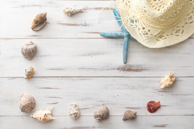 Concepto de fondo de verano estrellas de mar, conchas marinas, sombrero de paja en la superficie de madera clara