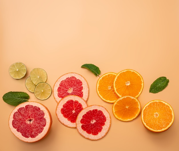 Concepto de fondo de verano en rodajas de naranja, pomelo, limón, lima, menta sobre fondo naranja