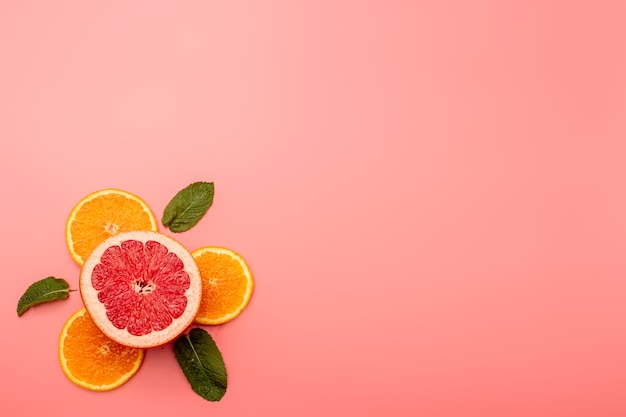 Concepto de fondo de verano en rodajas de naranja, pomelo, menta sobre fondo rosa