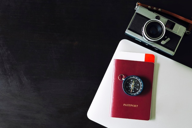 Concepto de fondo de viaje Pasaporte, brújula, cámara y laptop en mesa negra.