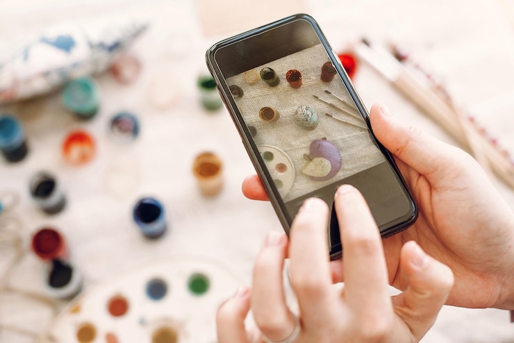 Foto concepto de fotografía de instagram y blogs manos sosteniendo el teléfono y tomando fotos del piso de pascua con huevos coloridos y pintura en la mesa feliz concepto de pascua
