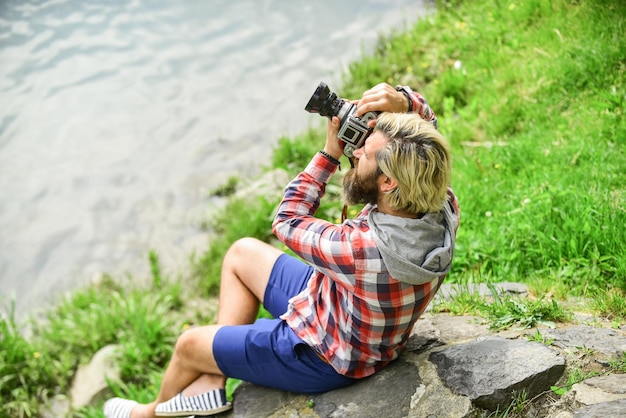 Concepto de fotógrafo Fotógrafo aficionado naturaleza fondo Creador de contenido Obra maestra tiro Hombre con barba disparando fotos Hombre barbudo hipster fotógrafo sostener cámara vintage