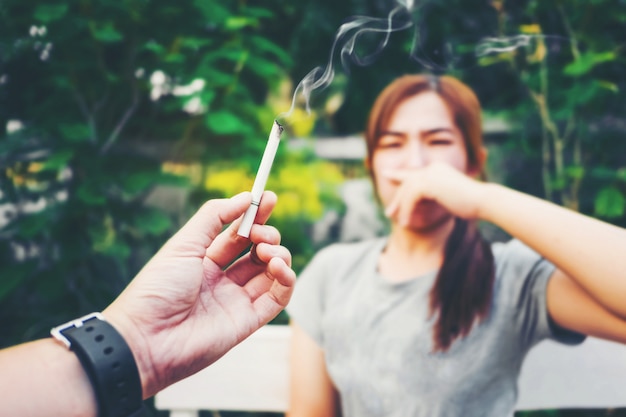 Concepto de fumar pasivo El hombre está fumando cigarrillo y la mujer se está cubriendo la cara, deja de fumar