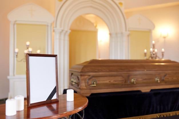 Foto concepto de funeral y luto - marco fotográfico con cinta negra, velas y ataúd en la iglesia