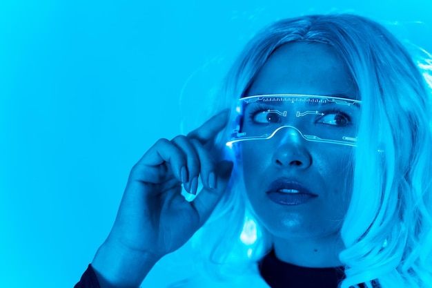 Concepto futurista una mujer joven con gafas de realidad virtual en un fondo azul