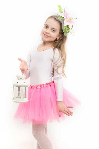 Concepto de futuro brillante. Sonrisa de niña con linterna de Navidad en tutú de falda rosa. Navidad, año nuevo, cumpleaños. Celebración navideña, aniversario. Niño con flor de pelo largo y rubio aislado en blanco.